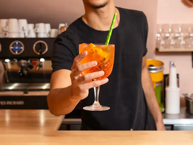 Verre de Spritz orangé à l'Aperol et Prosecco, garni d'une tranche d'orange fraîche, servi lors d'un apéritif à Paris Place d'Italie.