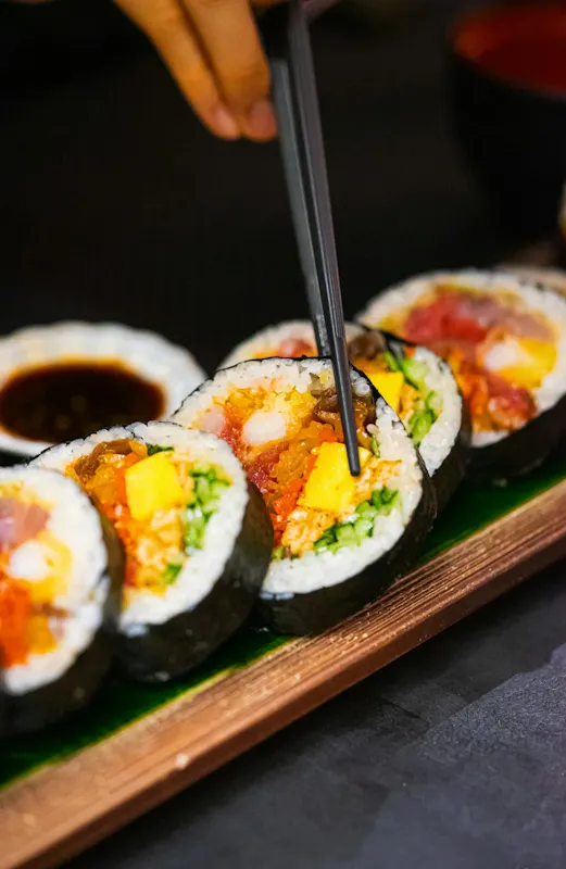 a person cutting into a sushi with chopsticks | Photo de susu jang, sur https://unsplash.com/@susustudio?utm_source=centralapp&utm_medium=referral