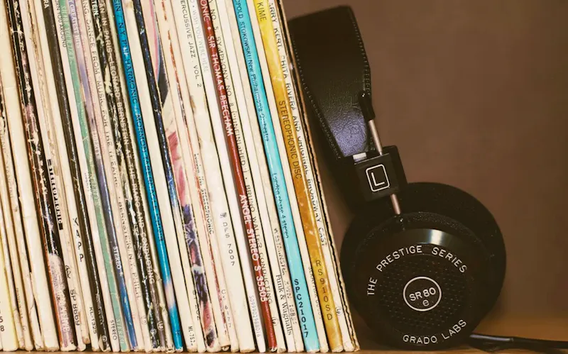 Black headphones resting against a row of vintage vinyl record albums | Photo de blocks, sur https://unsplash.com/@blocks?utm_source=CentralApp&utm_medium=referral