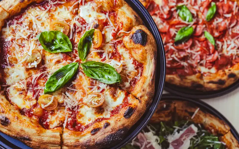 a couple of pizzas sitting on top of a table | Foto door Aldward Castillo, op https://unsplash.com/@aldwardcv31?utm_source=CentralApp&utm_medium=referral