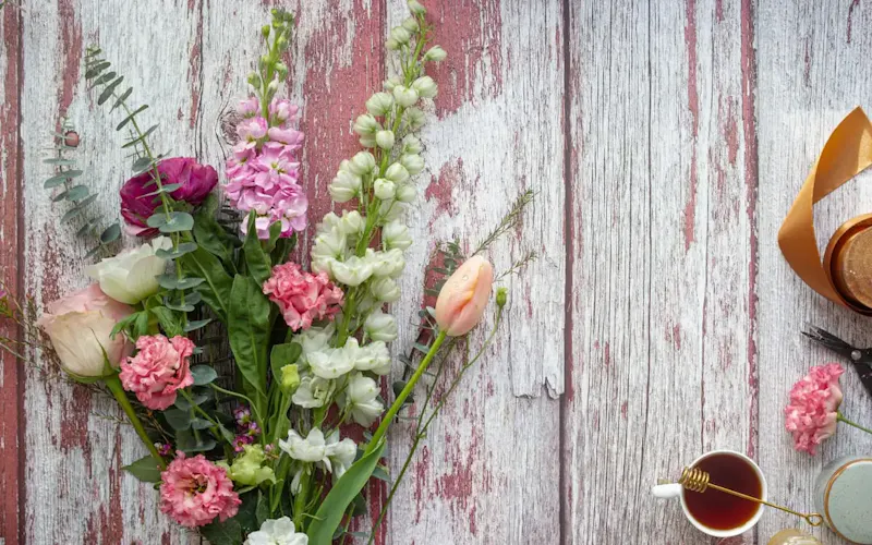 Image of Rishi's in Slate And Grain Brasserie & Bar pink flower on gray wooden plank | Photo by micheile henderson, on https://unsplash.com/@micheile?utm_source=centralapp&utm_medium=referral