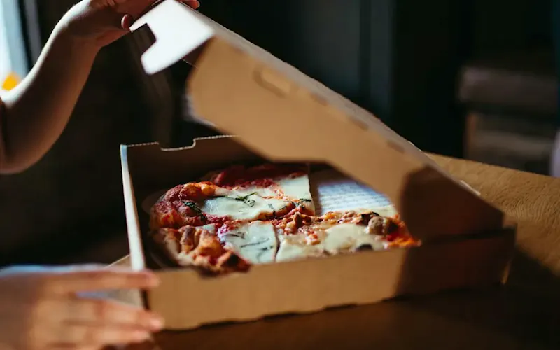 Image of Pizzeria Friggitoria zero81 a person holding a slice of pizza | Photo by Daniel, on https://unsplash.com/@unsplashbydan?utm_source=centralapp&utm_medium=referral