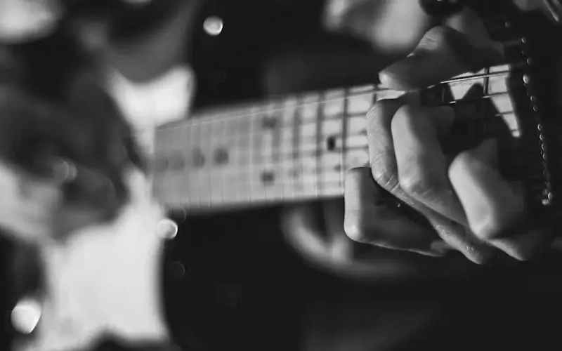 grayscale photo of person playing guitar | Photo by Austin Prock, on https://unsplash.com/@prock?utm_source=centralapp&utm_medium=referral