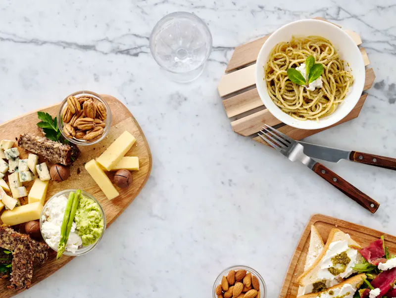 Elegant flat lay of assorted cheese, nuts, and pasta on a marble surface, perfect for food lovers. | Photo by Luna  Lovegood, on https://www.pexels.com/@luna-lovegood?utm_source=CentralApp&utm_medium=referral