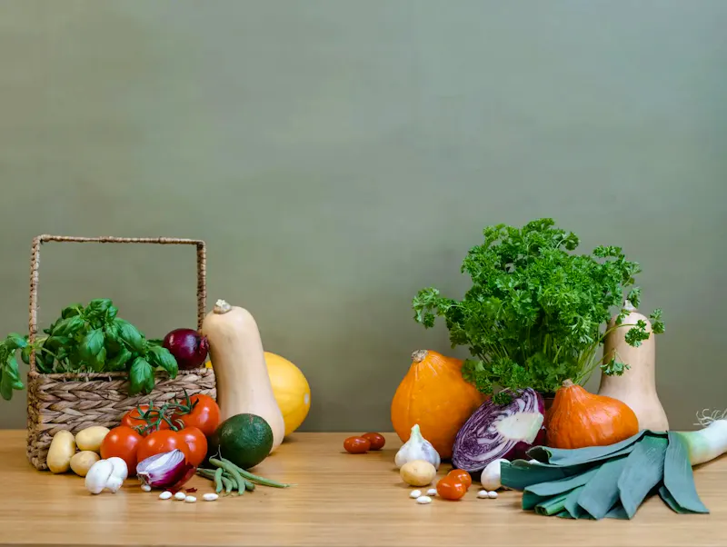 A variety of fresh vegetables including squash, tomatoes, and greens arranged on a wooden table. | 图片作者：MART  PRODUCTION, https://www.pexels.com/@mart-production?utm_source=centralapp&utm_medium=referral提供