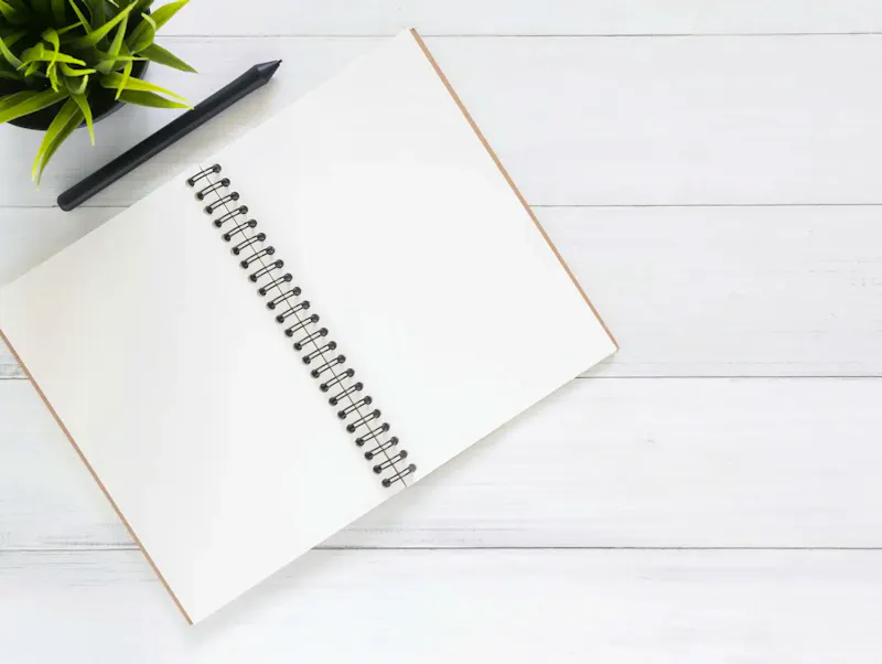 Open spiral notebook on white desk with black pen and green plant. Ideal for planning. | Photo by Tirachard Kumtanom, on https://www.pexels.com/@tirachard-kumtanom-112571?utm_source=centralapp&utm_medium=referral