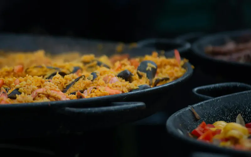 Appetizing close-up of traditional seafood paella cooking in a large outdoor pan. | Photo de Александр Лич, sur https://www.pexels.com/@lich?utm_source=centralapp&utm_medium=referral