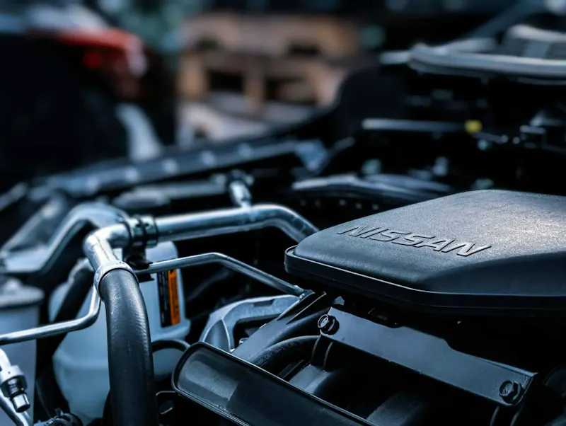 Detailed view of a car engine compartment with visible Nissan branding. | Immagine di Obi Onyeador, su https://www.pexels.com/@obi-onyeador-1787470?utm_source=centralapp&utm_medium=referral