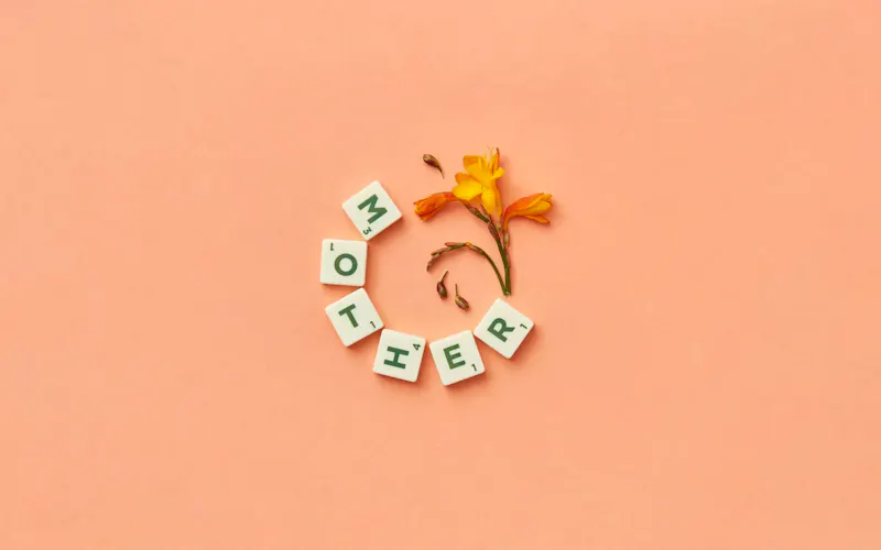 Image of Le Manège Scrabble tiles spelling 'mother' with flowers on peach background, perfect for Mother's Day. | Photo by DS stories, on https://www.pexels.com/@ds-stories?utm_source=CentralApp&utm_medium=referral