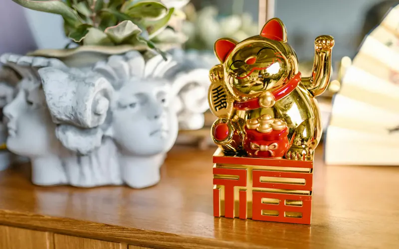 A Golden Lucky Cat figurine symbolizing good fortune and prosperity, displayed indoors. | Photo by RDNE Stock project, on https://www.pexels.com/@rdne?utm_source=centralapp&utm_medium=referral