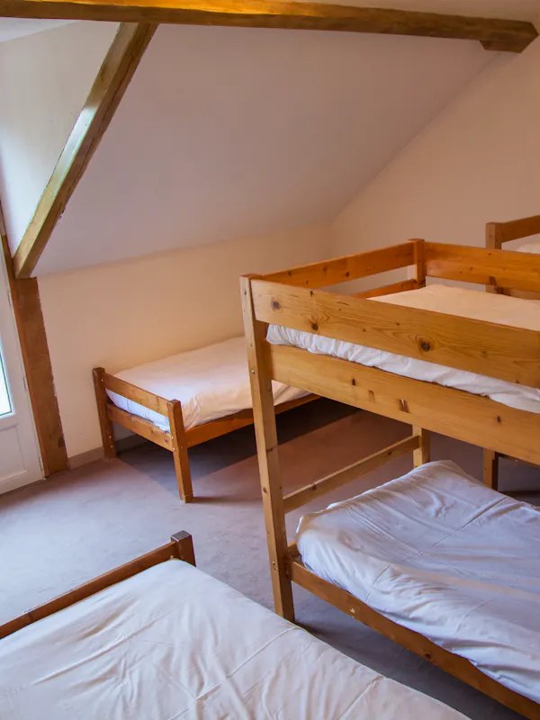 Chambre confortable pour sept personnes, équipée de lits simples et de lits superposés, avec salle de bain et toilettes privatives. Petit-déjeuner inclus.