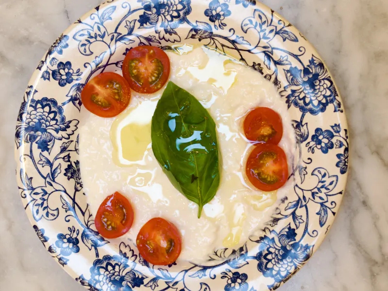 Gros plan sur la Stracciatella di Bufala de notre restaurant italien Place d'Italie. La texture crémeuse de la burrata est mise à l'honneur pour une expérience dégustation authentique dans le 13ème arrondissement.