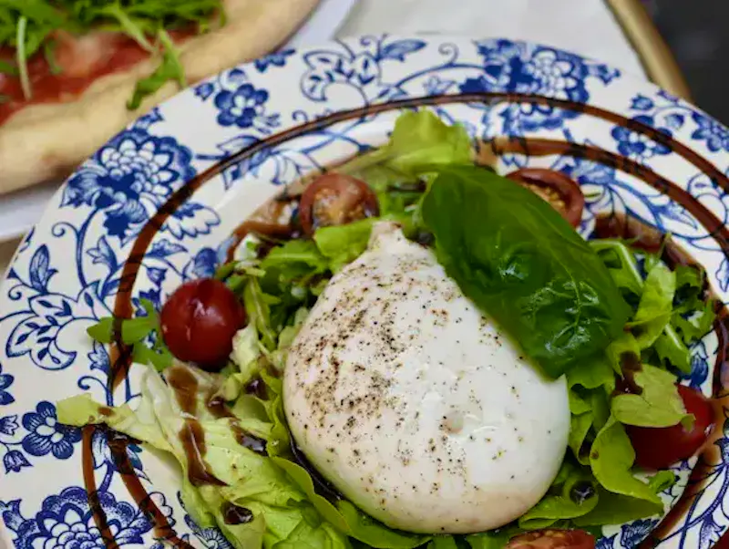 Véritable Burratina des Pouilles servie sur un lit de tomates cerises juteuses chez Ti Amo Châtelet. Une entrée italienne classique et rafraîchissante, idéale pour un déjeuner au cœur de Paris.