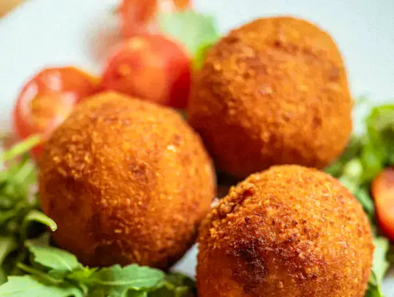 Arancini dorés et croustillants au restaurant Ti Amo Châtelet : boulettes de riz panées farcies à la mozzarella fondante, sauce tomate savoureuse et jambon cuit. Une spécialité sicilienne incontournable au cœur de Paris.