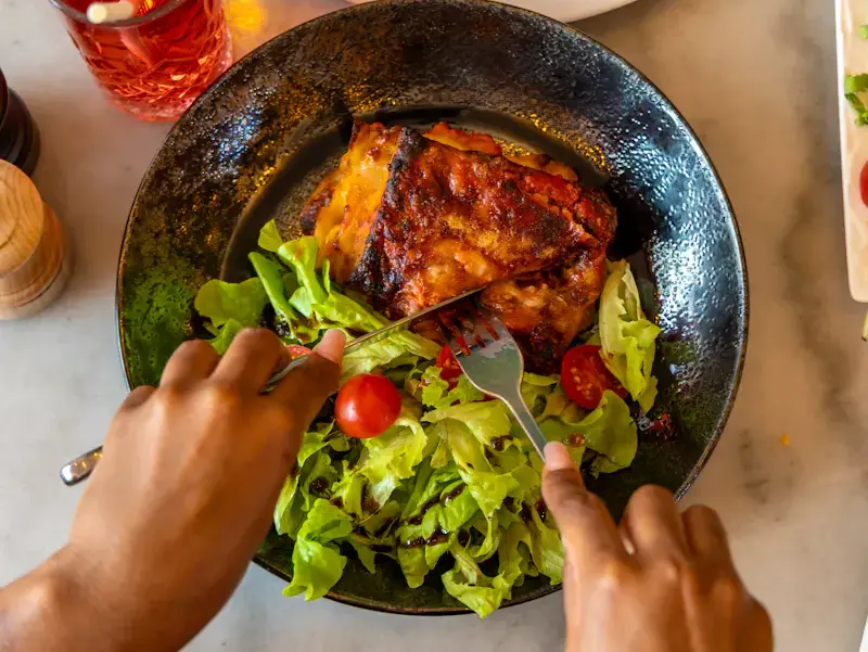Une part généreuse de lasagne bolognese gratinée servie sur un lit de salade fraîche et tomates cerises chez Ti Amo Châtelet. Un plat italien authentique et Halal au cœur de Paris.