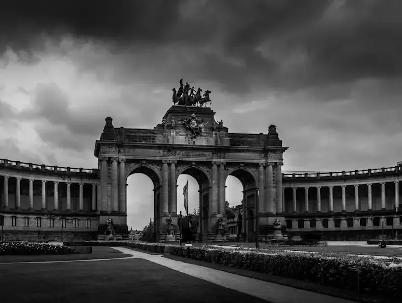 a large building with a clock tower with Cinquantenaire in the background | Photo by Gabriel Helou, on https://unsplash.com/@gabrielhelou?utm_source=centralapp&utm_medium=referral