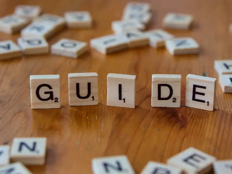 A wooden table topped with scrabble tiles spelling the word guide | Immagine di Markus Winkler, su https://unsplash.com/@markuswinkler?utm_source=centralapp&utm_medium=referral