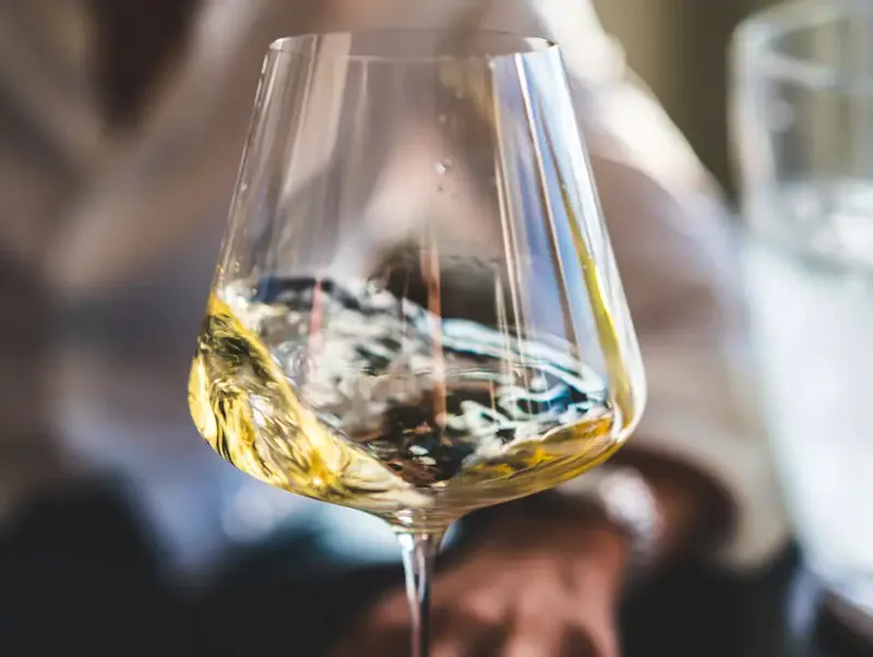 Image of Tcham Wine clear wine glass with yellow liquid | Photo by Big Dodzy, on https://unsplash.com/@bigdodzy?utm_source=CentralApp&utm_medium=referral