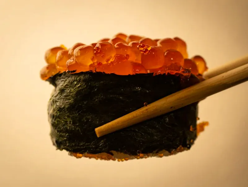 a close up of a sushi with chopsticks | Photo by blackieshoot, on https://unsplash.com/@blackieshoot?utm_source=CentralApp&utm_medium=referral